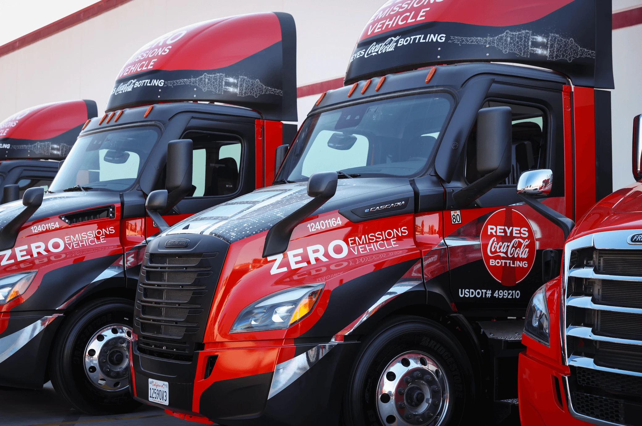 A group of "RCCB Zero Emissions" trucks parked in front of a warehouse building